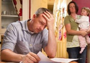 Man stresses over his bill while his wife and child stand in the background.